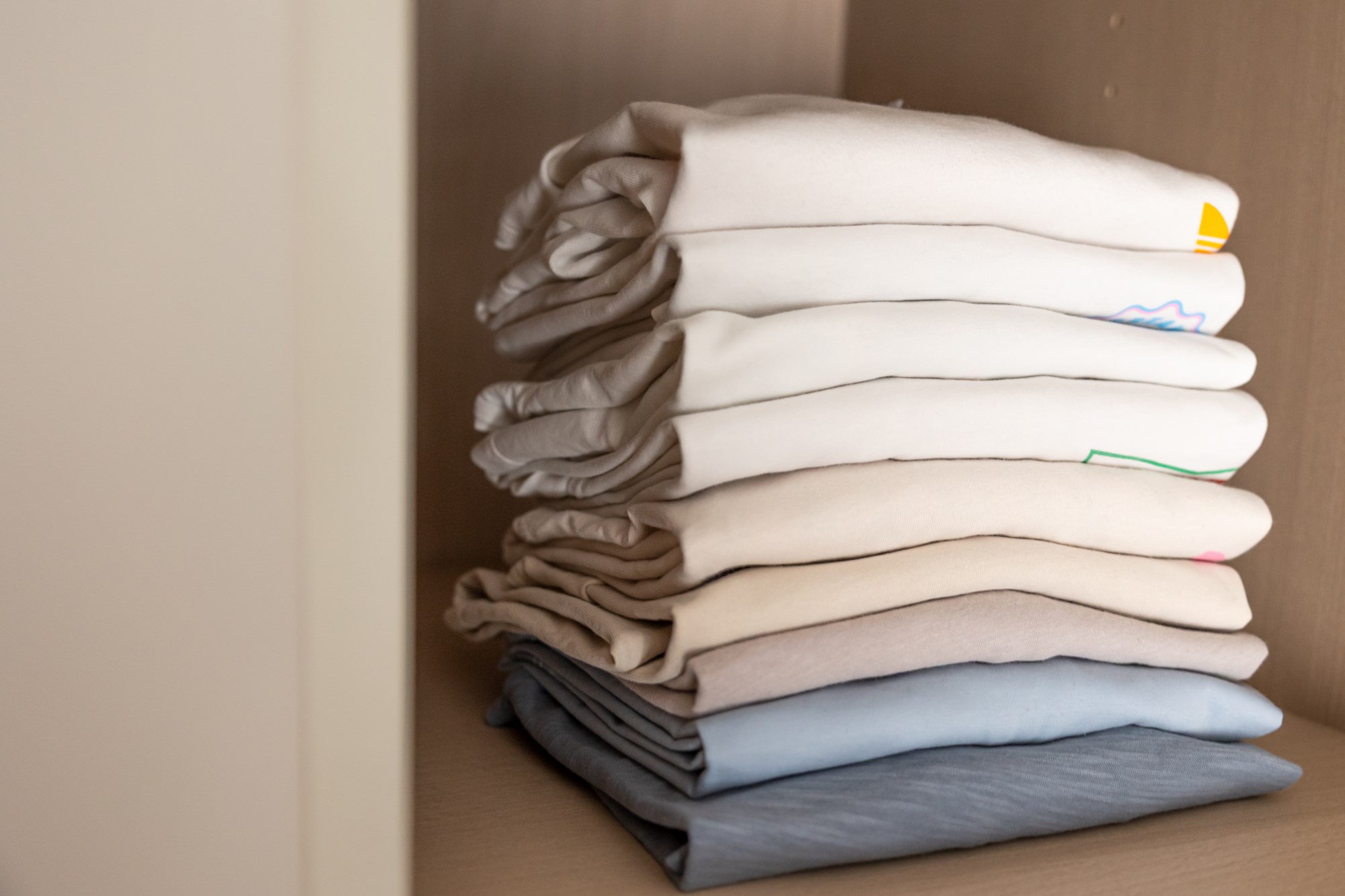 Folded t-shirts stacked on wardrobe shelf