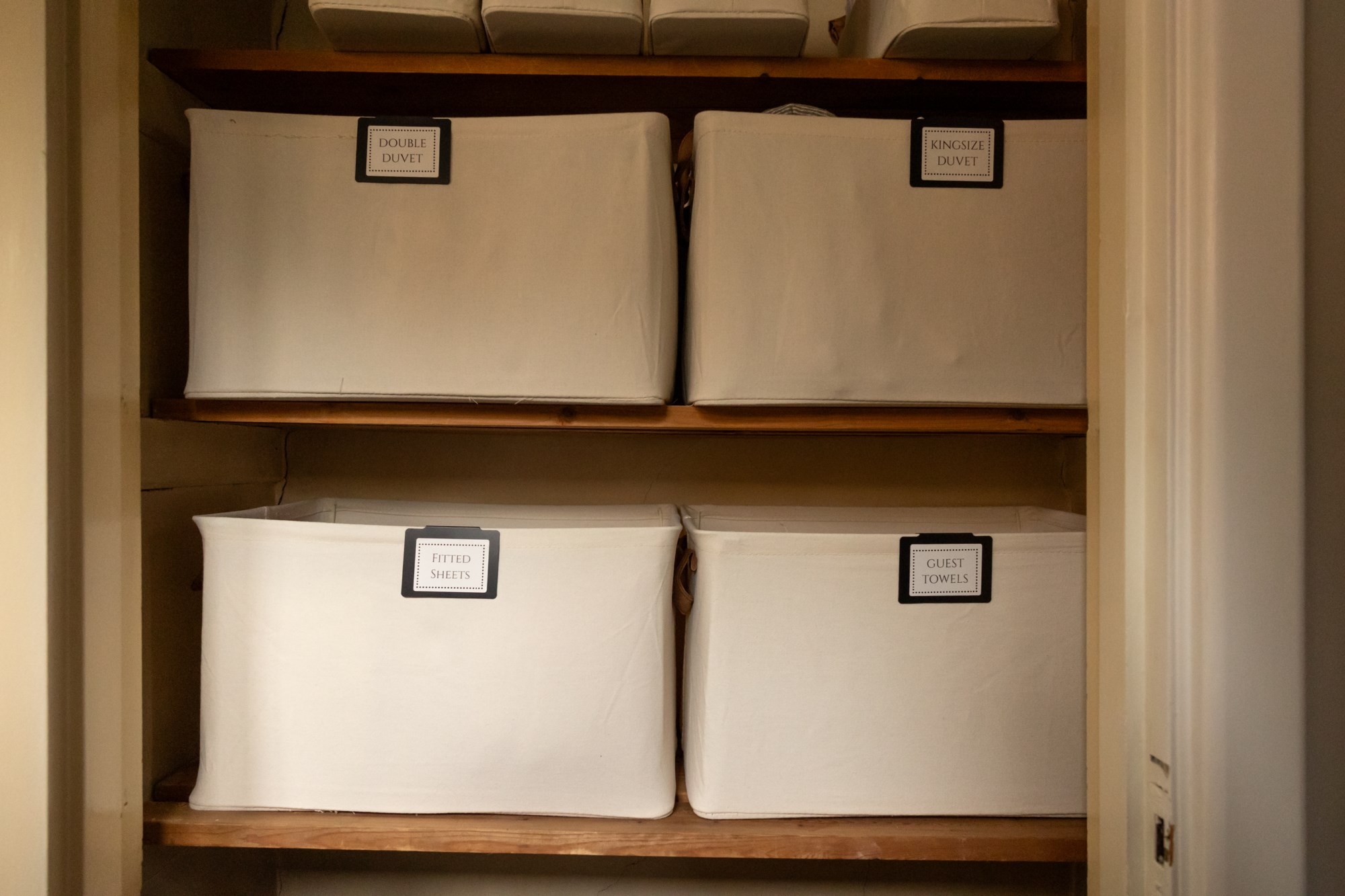 Labelled linen storage boxes in cupboard